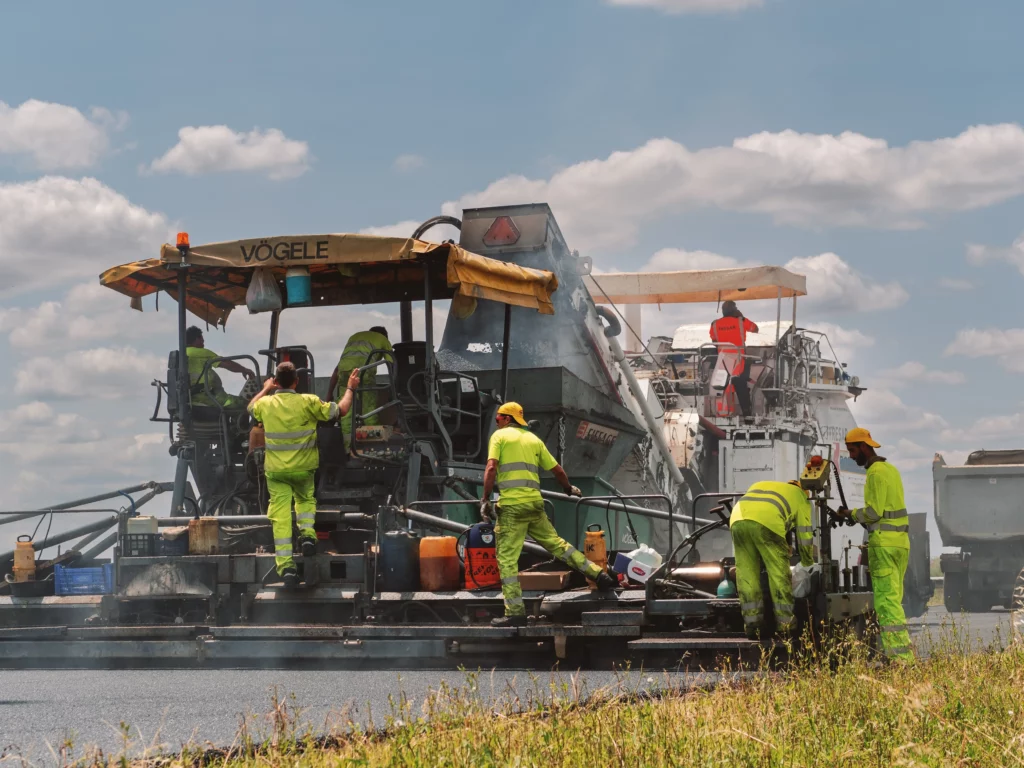 obreros de Collosa asfaltando carretera con maquinaria pesada